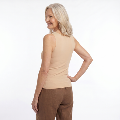 Woman wearing a beige sleeveless top and brown pants on a white background
