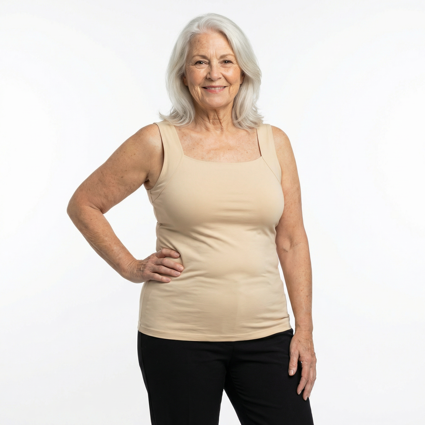 Woman wearing a beige tank top and black pants on a white background